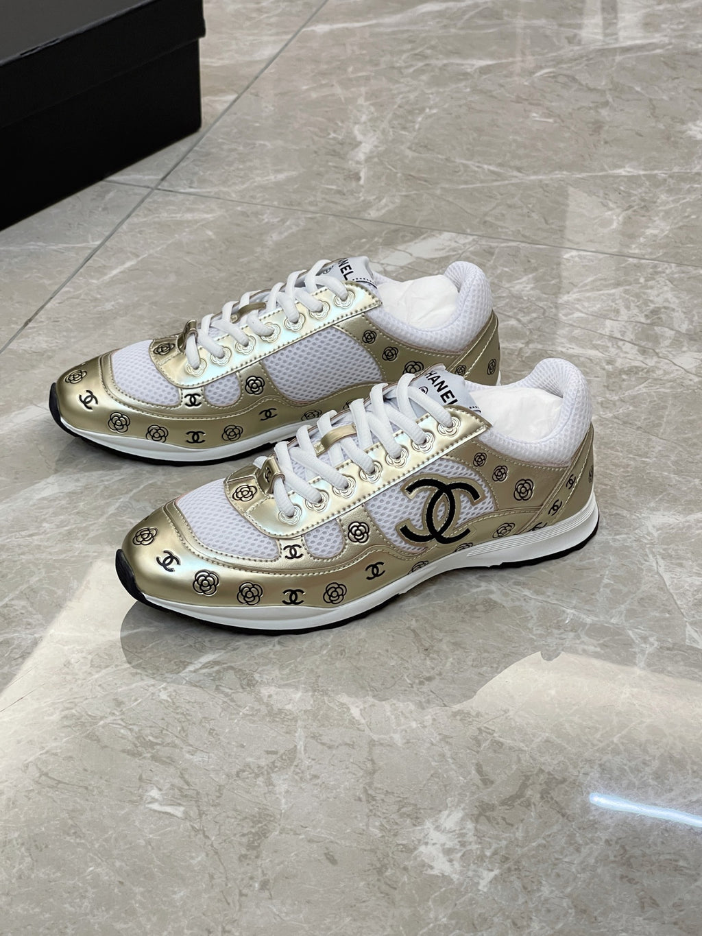 Unisex sneakers pair, white upper with gold logo panel and white rubber sole