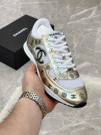 Unisex sneaker in hand, gold and white side panel with logo and white laces