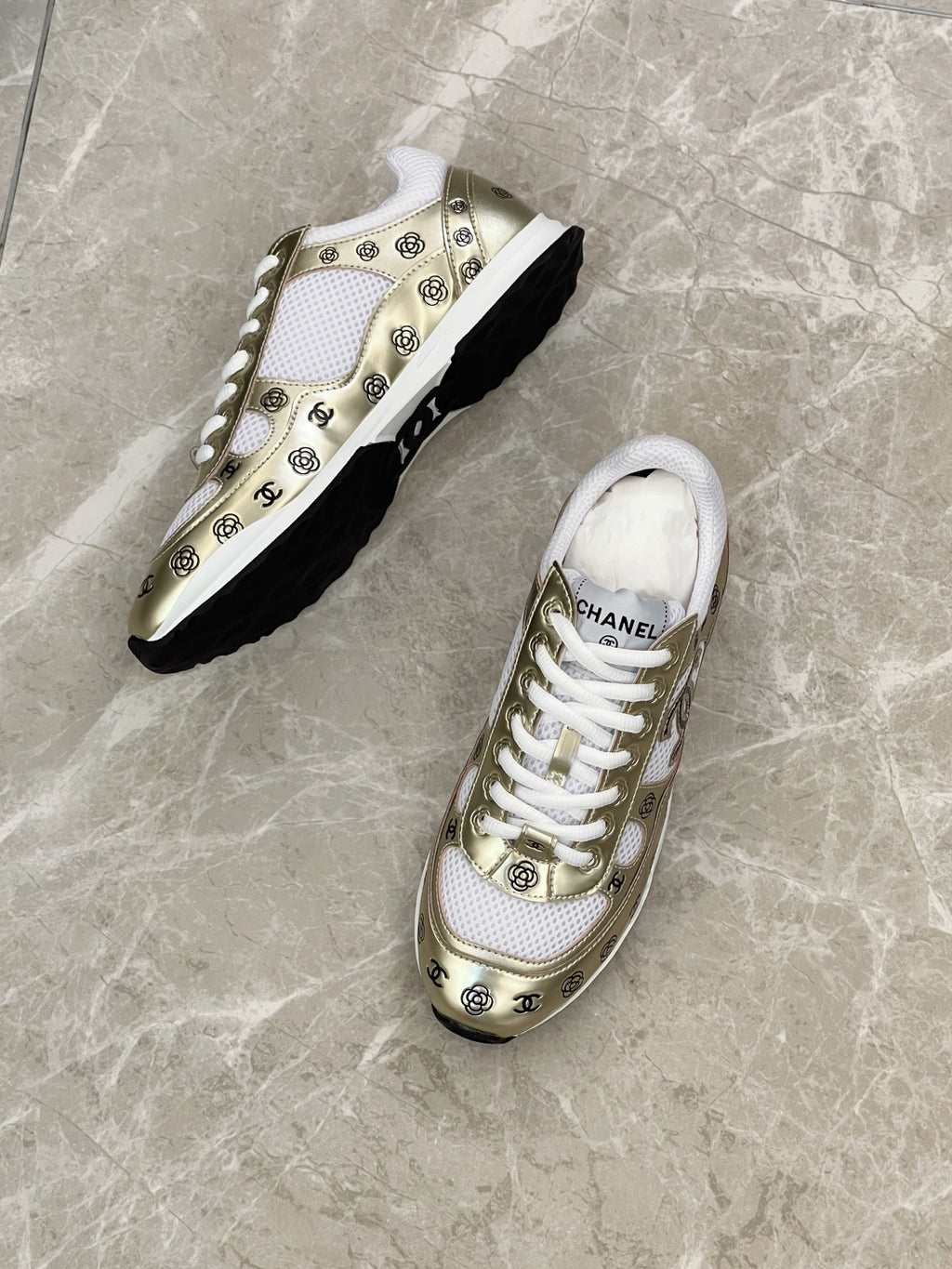 Unisex sneakers, white and gold uppers with logo pattern, on black soles