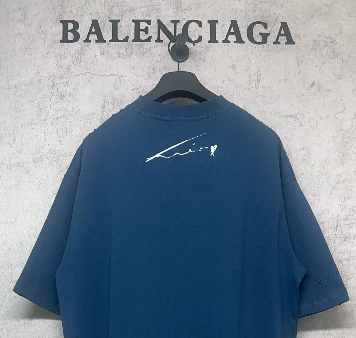 Blue graphic T-shirt back with white signature-style graphic
