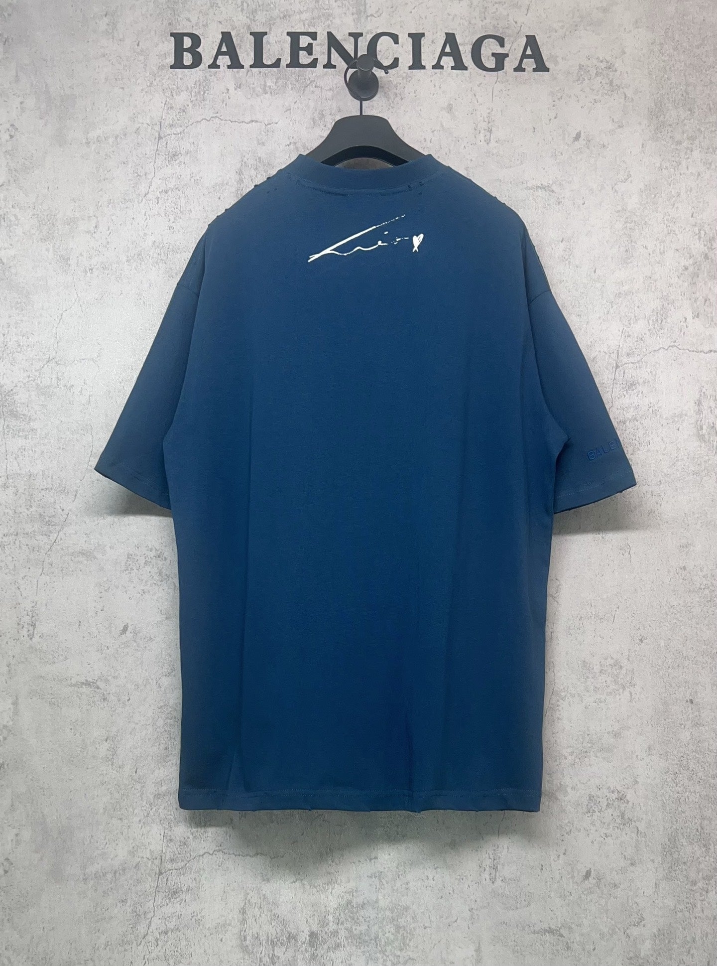 Blue graphic T-shirt back with small white signature-style print
