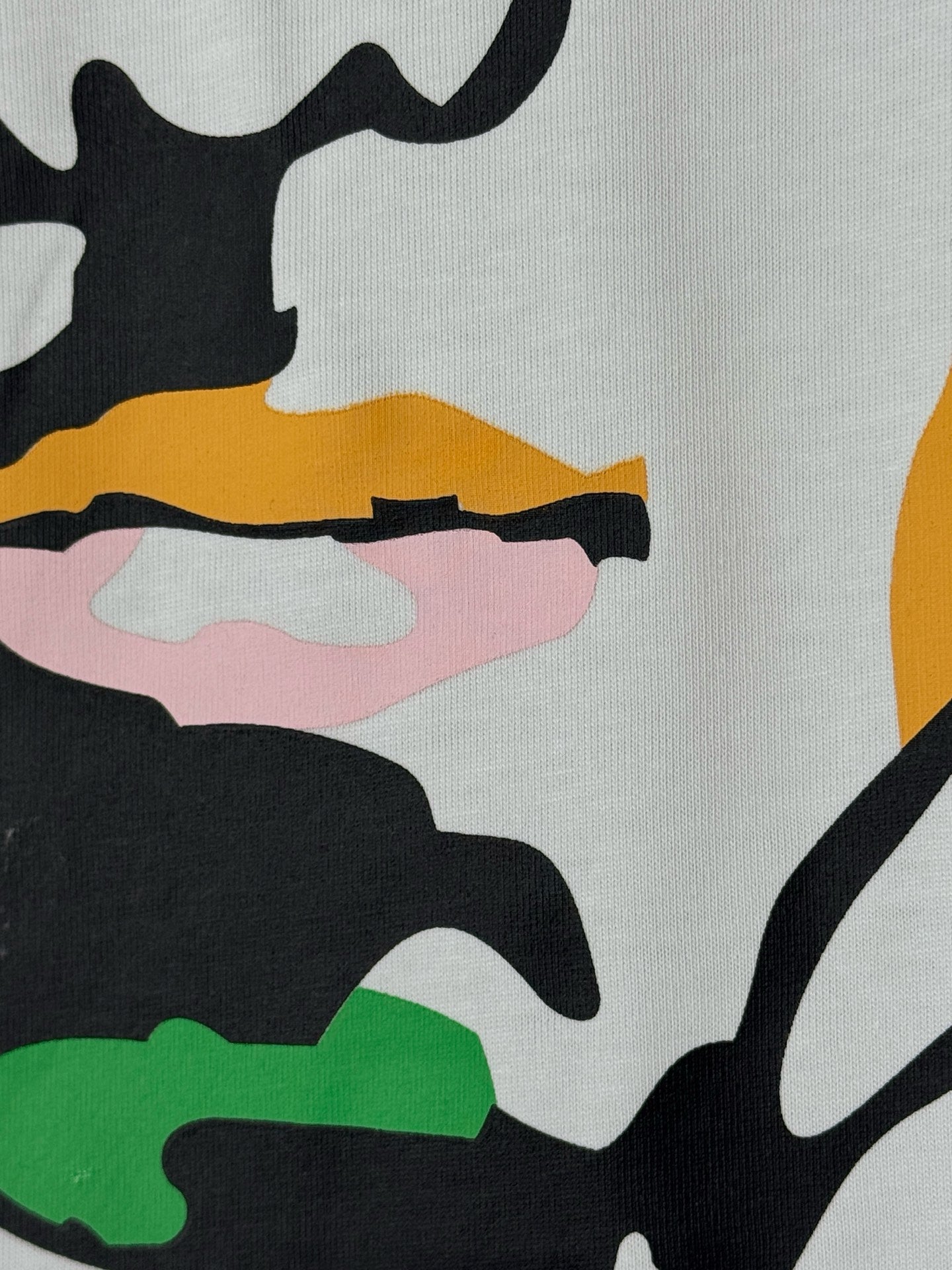 White graphic T-shirt fabric detail with colorful face features
