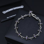 Silver charm bracelet with purple flower accents, shown on a dark gift box