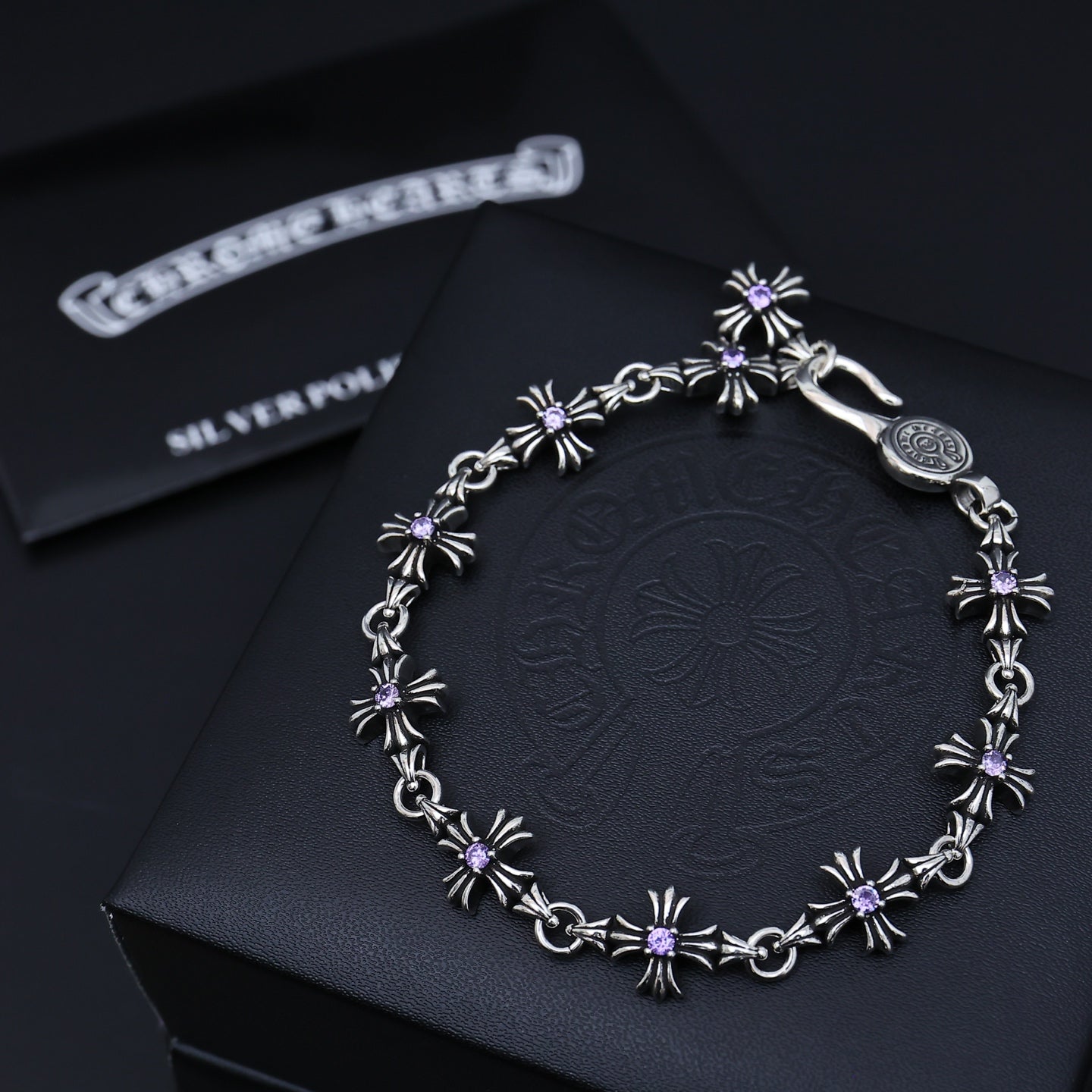Silver charm bracelet with purple flower accents, shown on a dark gift box