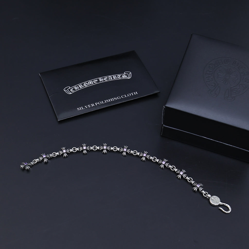 Silver charm bracelet with purple accents and a silver polishing cloth card