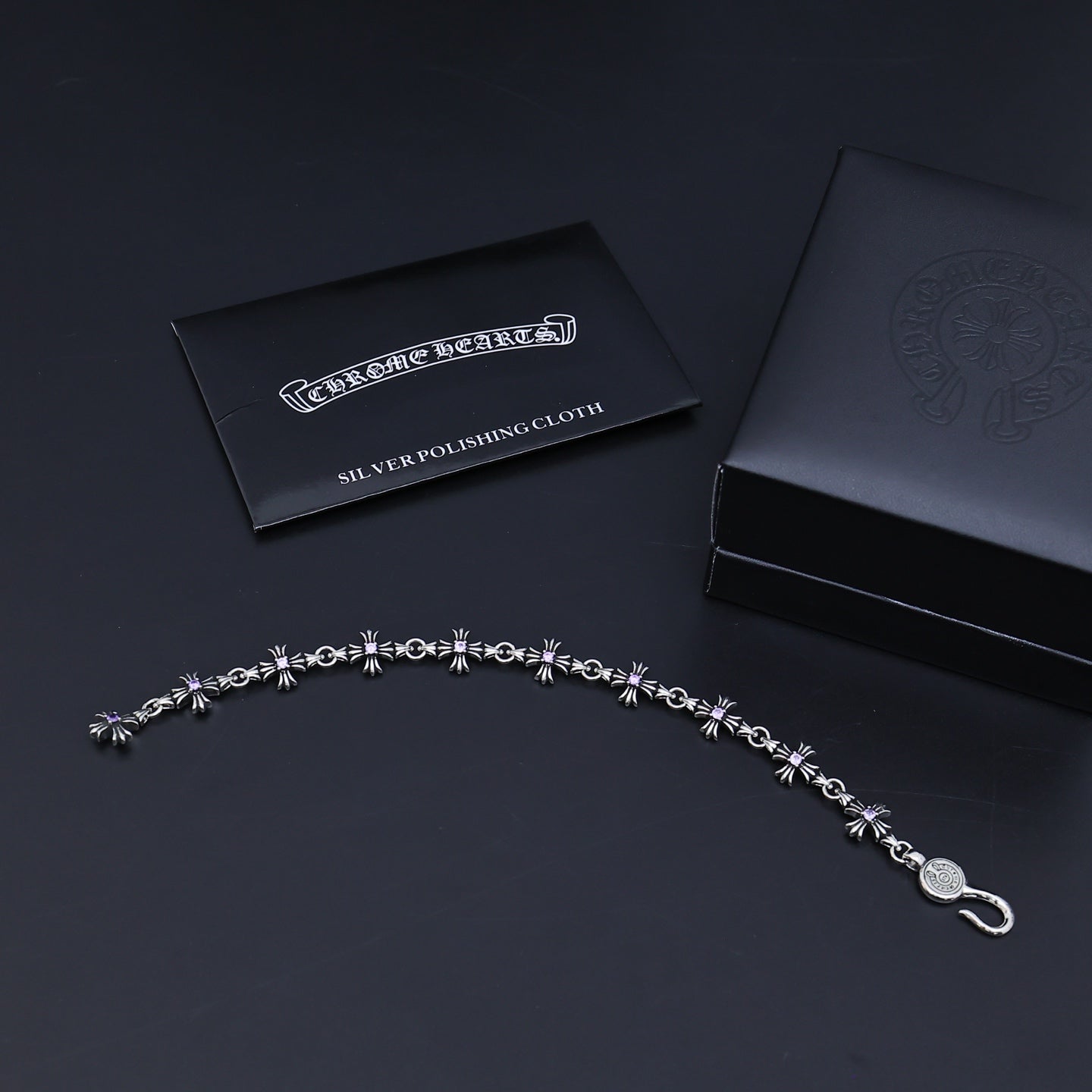 Silver charm bracelet with purple accents and a silver polishing cloth card