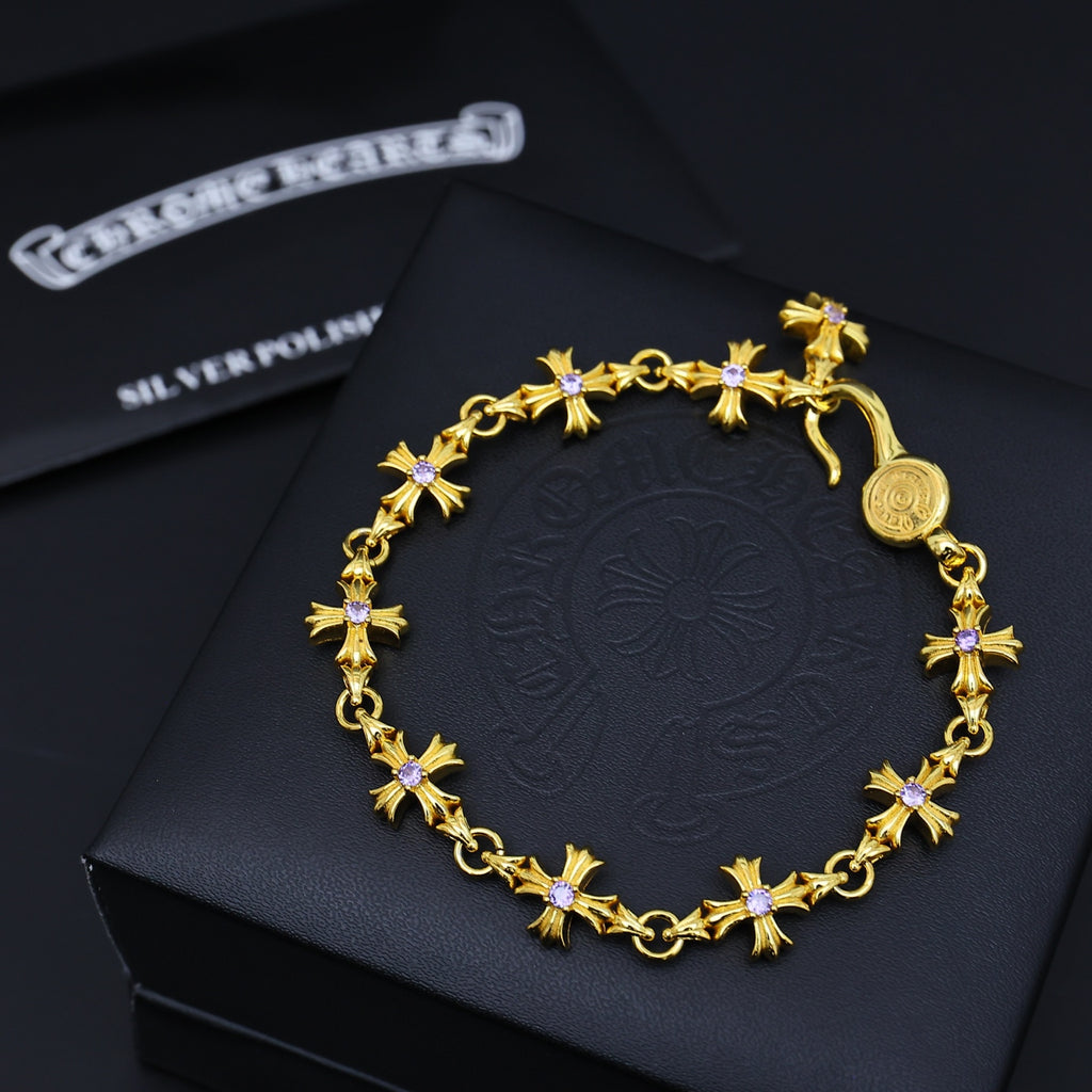 Gold charm bracelet with purple flower accents, displayed on a dark gift box