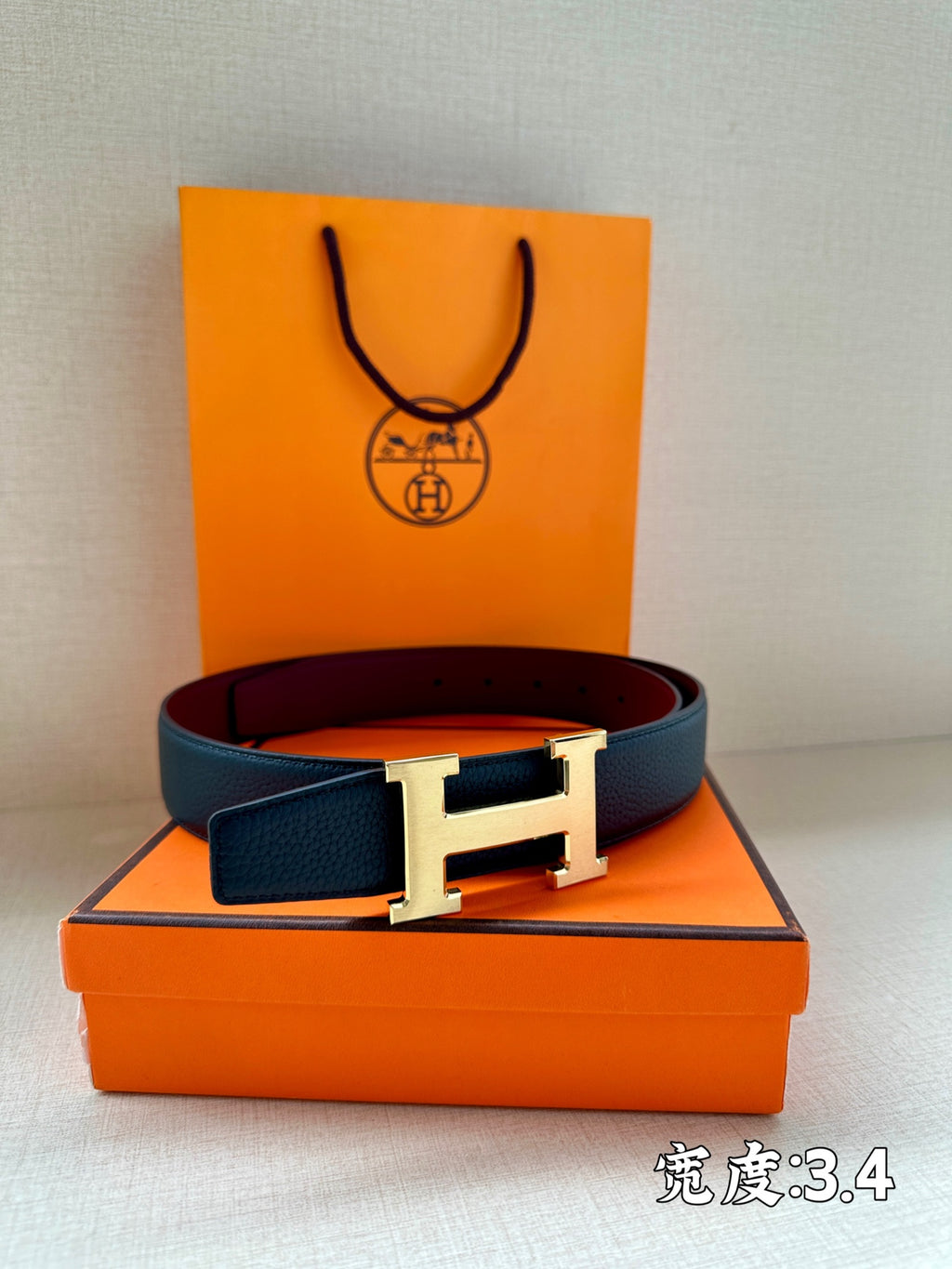 Navy leather belt with silver H buckle on orange presentation box.