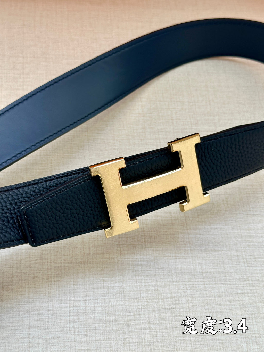 Hermes belt strap detail with dark navy leather and gold-tone H buckle