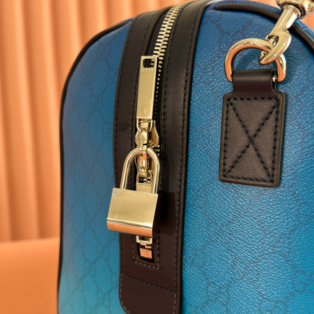 Gucci bag blue GG pattern with gold lock hardware and brown leather key fob.