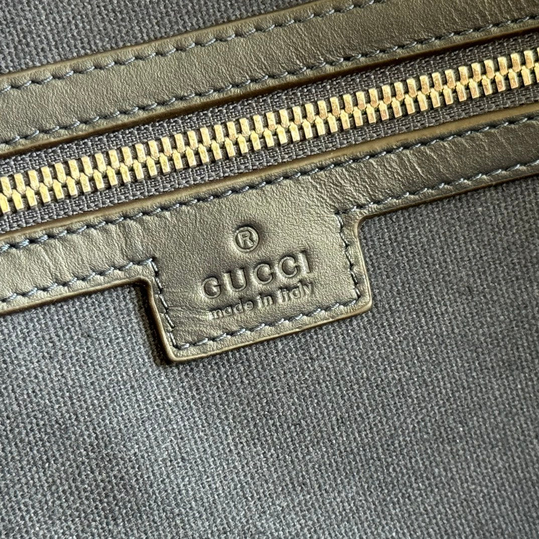 Gucci bag leather logo patch with gold zipper trim and stitched edging.