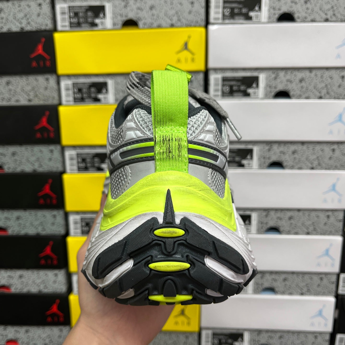 Grey running sneaker heel view, neon yellow midsole band and treaded outsole