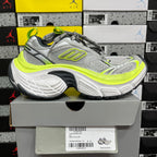 Grey and neon yellow running sneaker on box, side view with lace-up closure