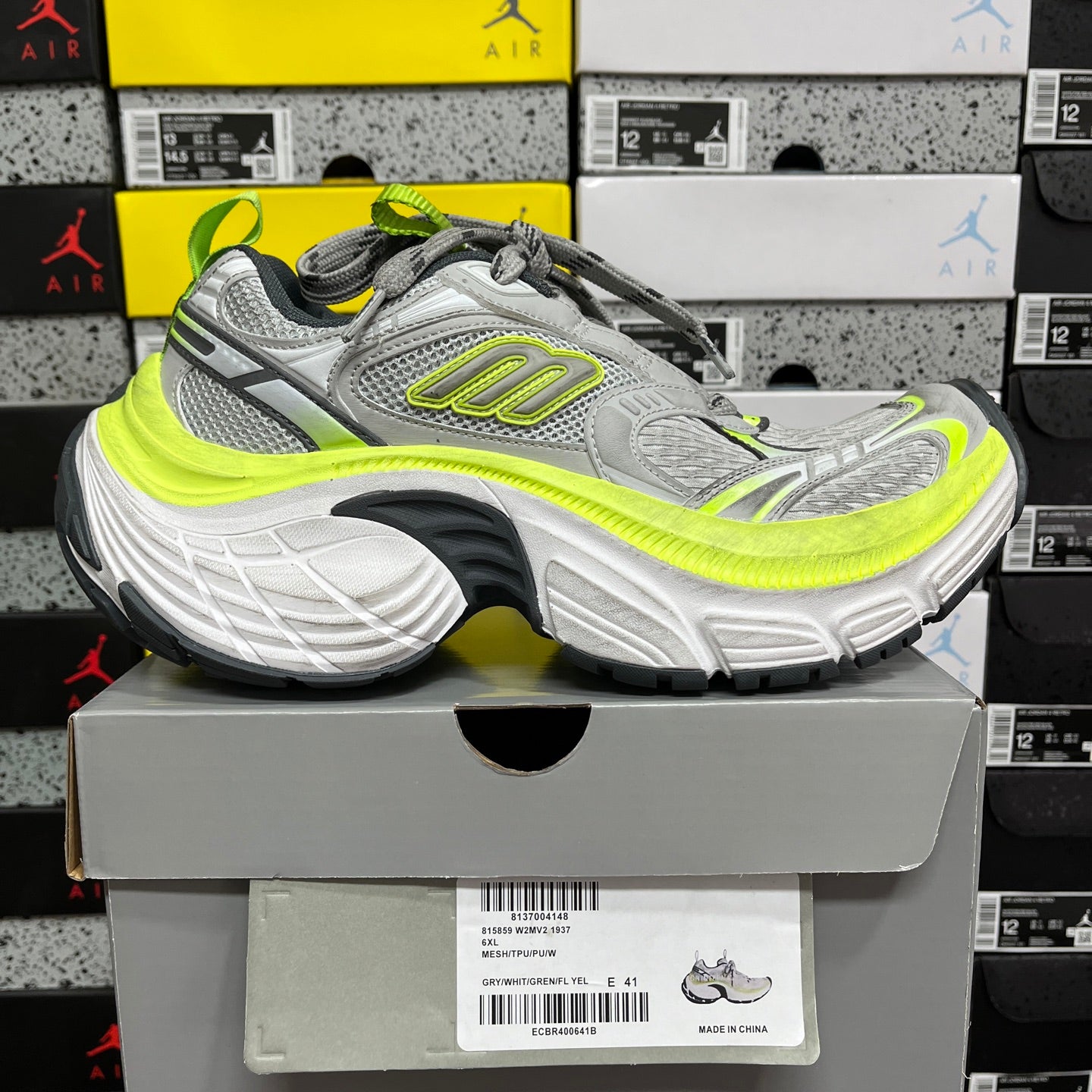Grey and neon yellow running sneaker on box, side view with lace-up closure