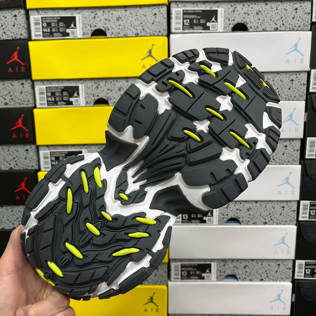 Grey and black sneaker outsole with neon yellow traction highlights