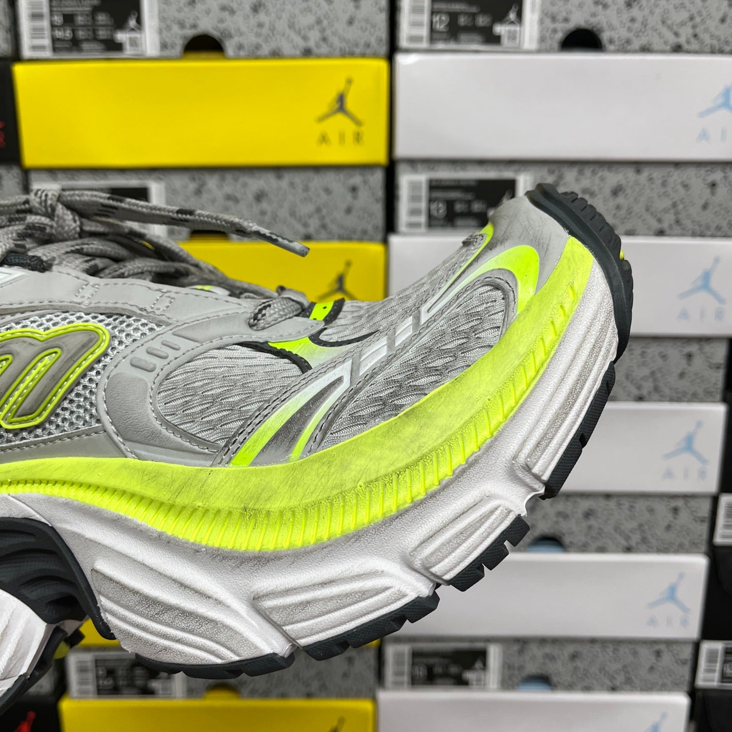 Grey and neon yellow running sneaker, angled side view with chunky tread sole