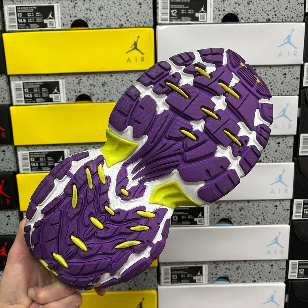 Outsole view of purple sneakers with textured tread and neon lime traction spots