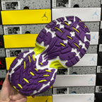 Outsole view of purple sneakers with textured tread and neon lime traction spots