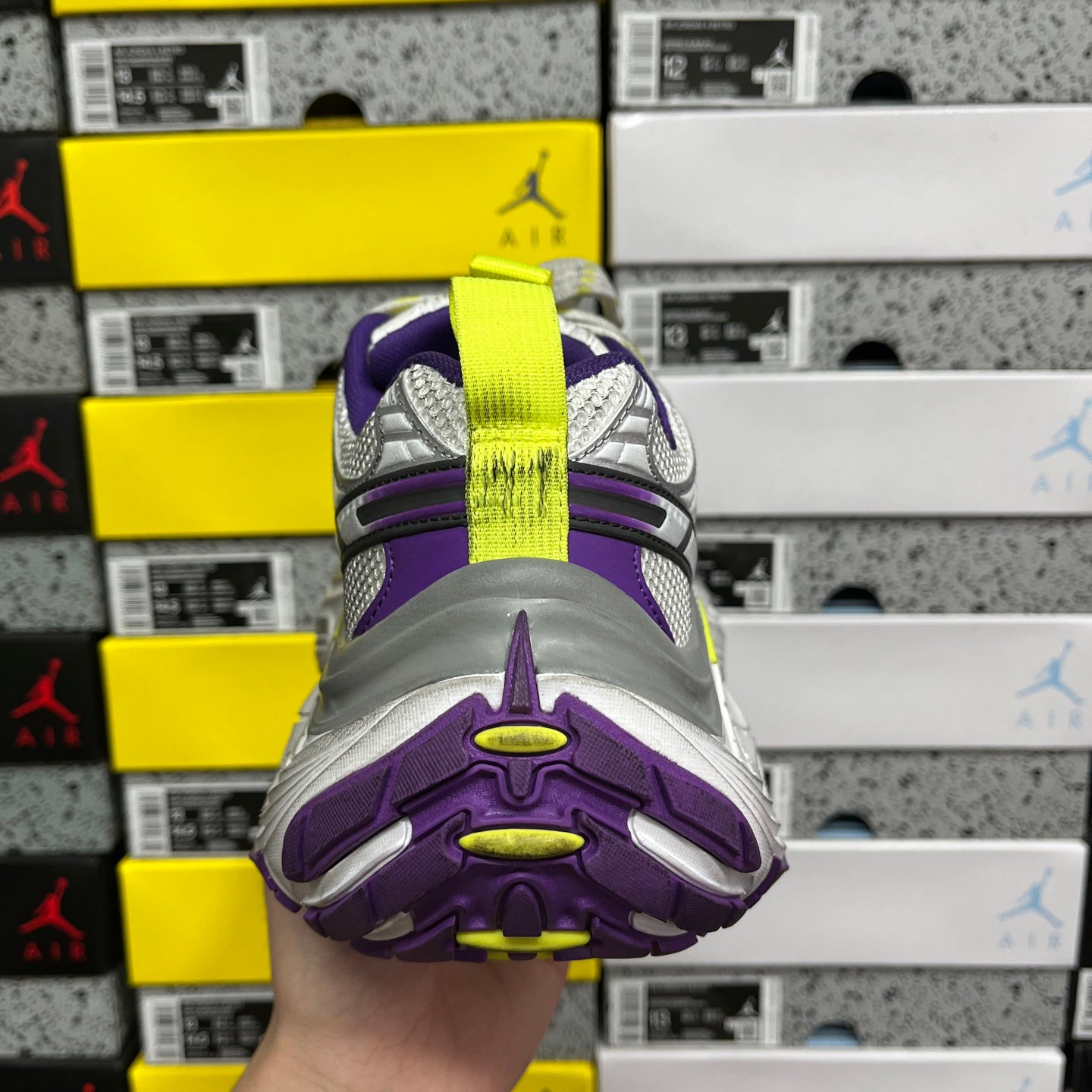 Sole-and-heel view of sneakers with purple tread and neon green highlight accents