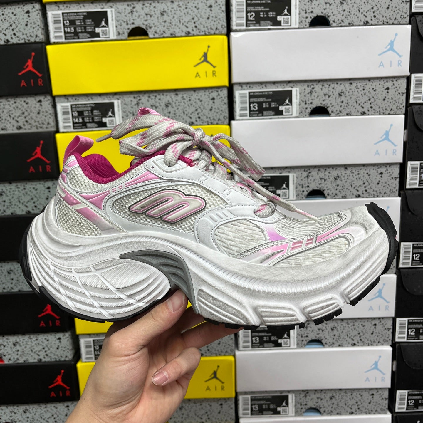 White sneaker with pink and gray accents, multicolor laces, and thick sole
