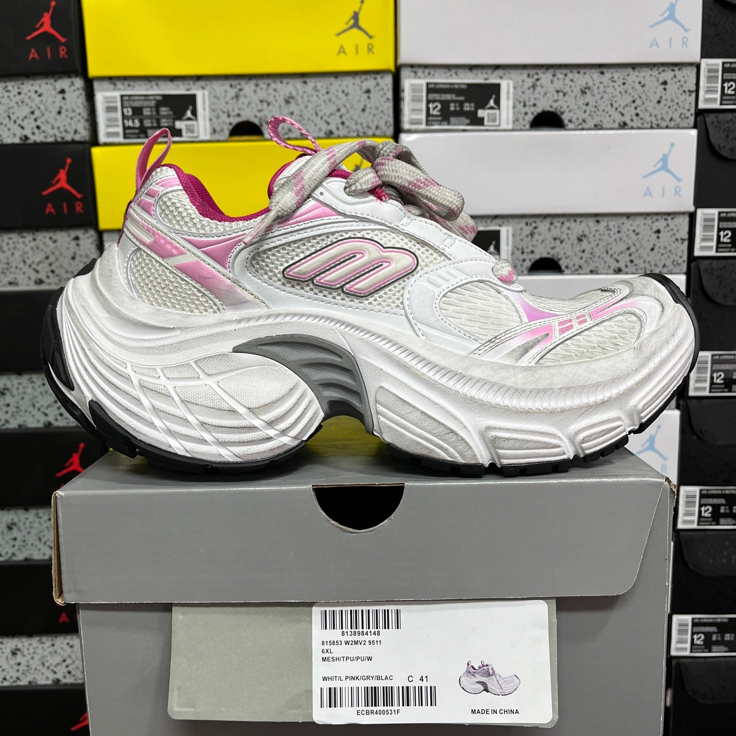 White lace-up sneaker with pink trim, chunky sole, and side logo detail
