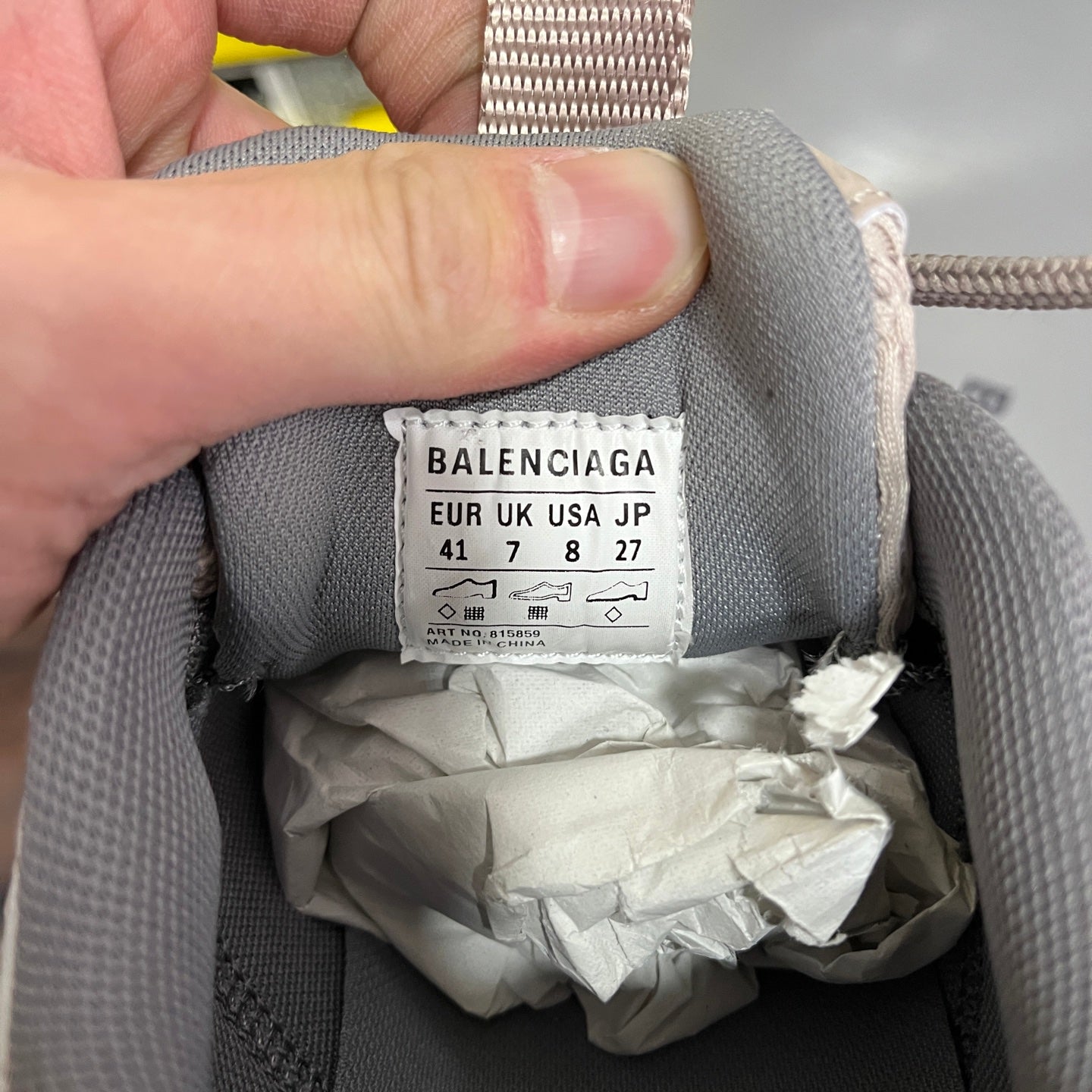 Light gray sneaker interior label with size and region codes, stitched on collar