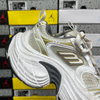 White Balenciaga sneakers with gold logo panel and white laces, chunky sole tread.