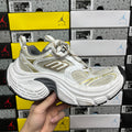 White Balenciaga sneakers with gold accents, mesh panels, chunky rubber sole, lace-up.