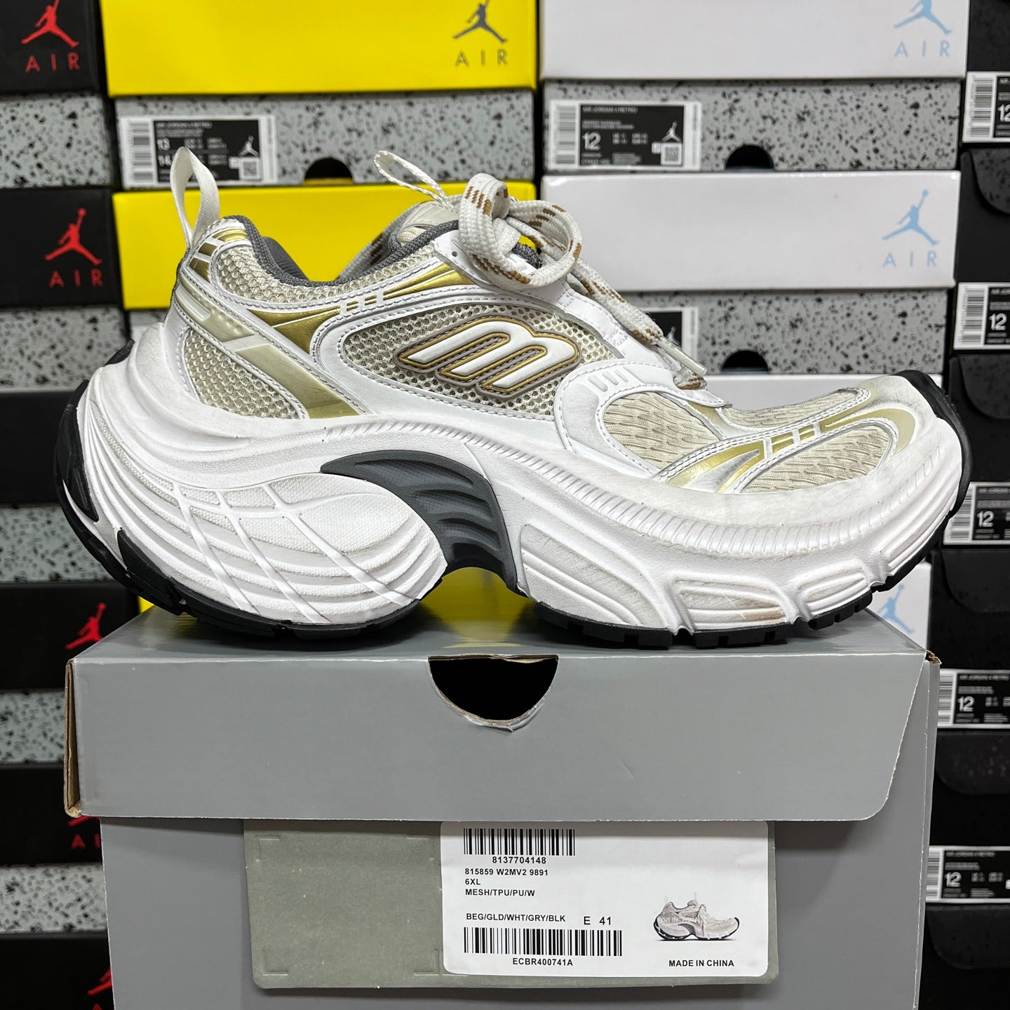 White Balenciaga sneakers with gold trim, thick sculpted sole, lace-up closure.
