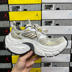 White Balenciaga sneakers with gold details, mesh upper and thick rubber sole, lace-up.