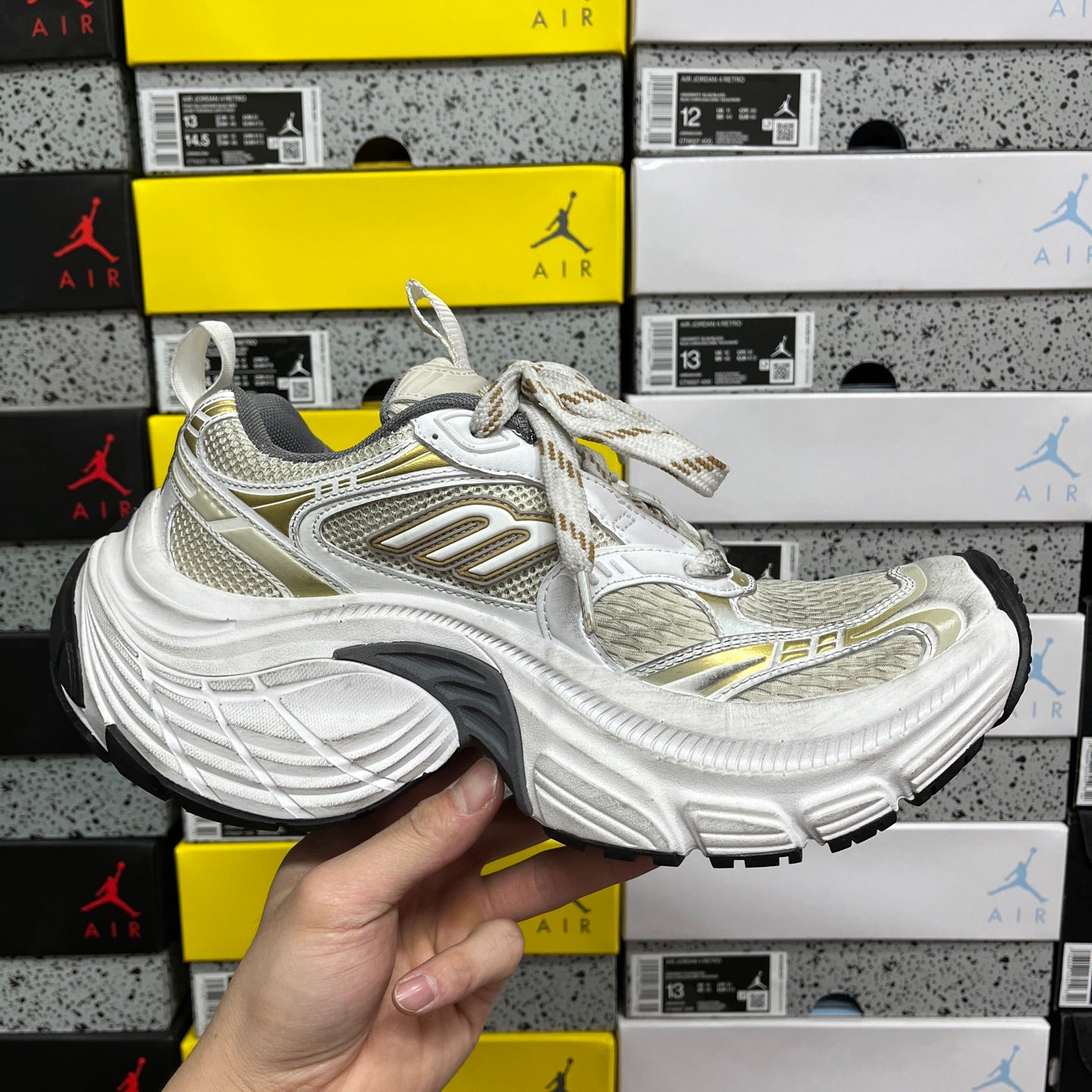 White Balenciaga sneakers with gold details, mesh upper and thick rubber sole, lace-up.