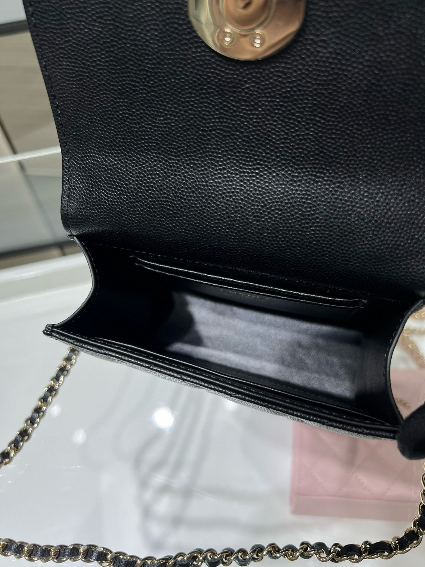 Black Chanel mini bag with open flap and chain strap, showing interior lining