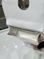 Chanel white leather bag with open flap and gold hardware on textured exterior
