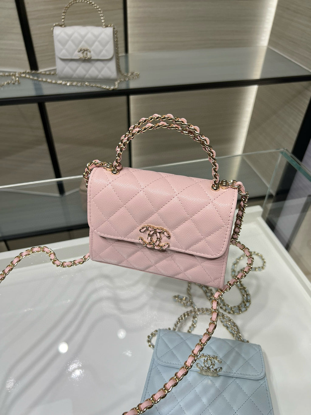 Pink quilted crossbody handbag with short top handle, gold clasp, and chain