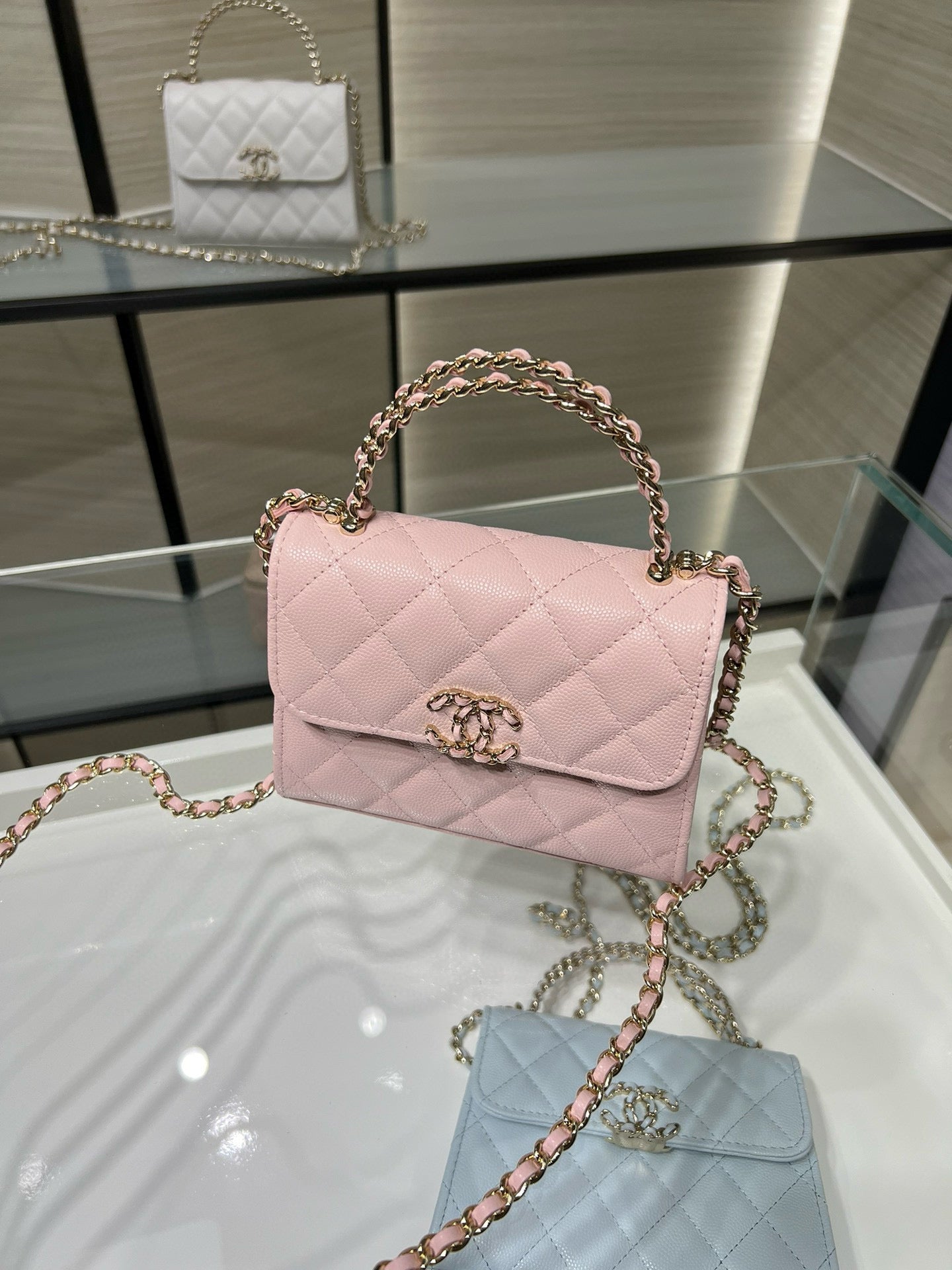 Pink quilted crossbody handbag with short top handle, gold clasp, and chain