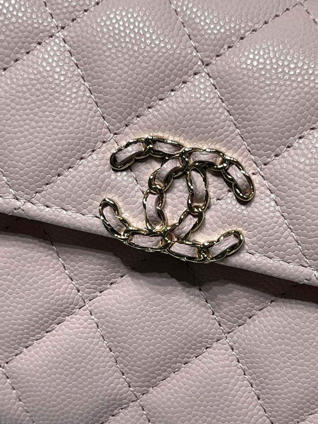 Close-up of quilted pink leather handbag flap hardware and ring clasp