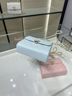 Light blue quilted flap crossbody bag with gold-tone emblem and chain strap
