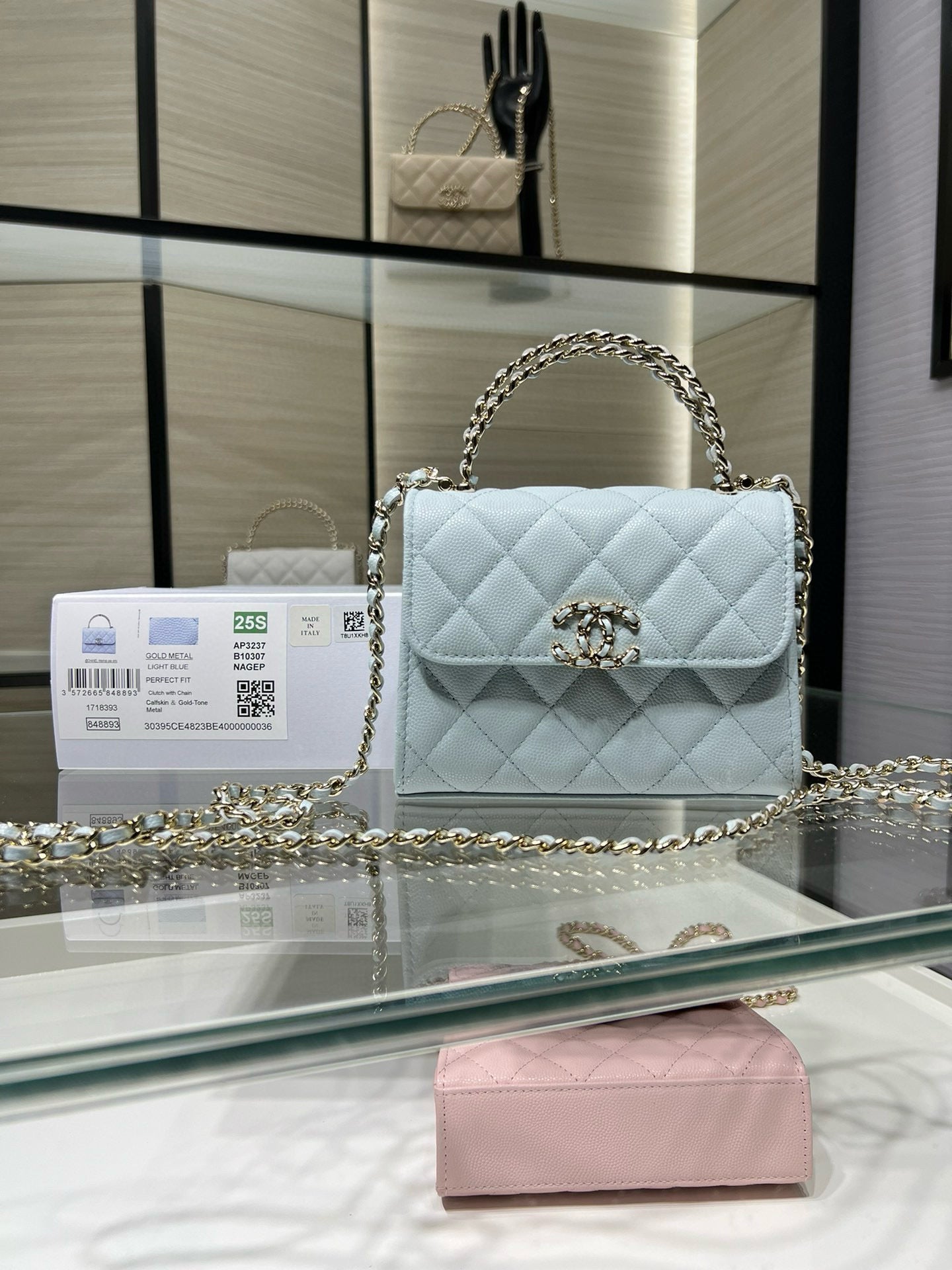 Light blue quilted flap crossbody bag with gold-tone chain strap and emblem clasp