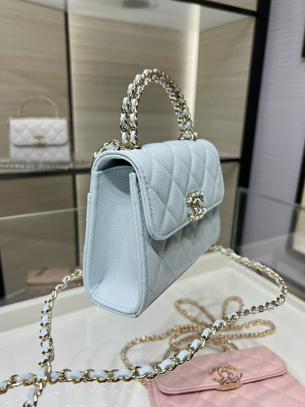 Light blue quilted flap handbag with gold-tone emblem and chain shoulder strap