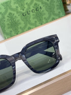 Gucci close-up of dark tinted lens and thick navy frame, temple and bridge visible