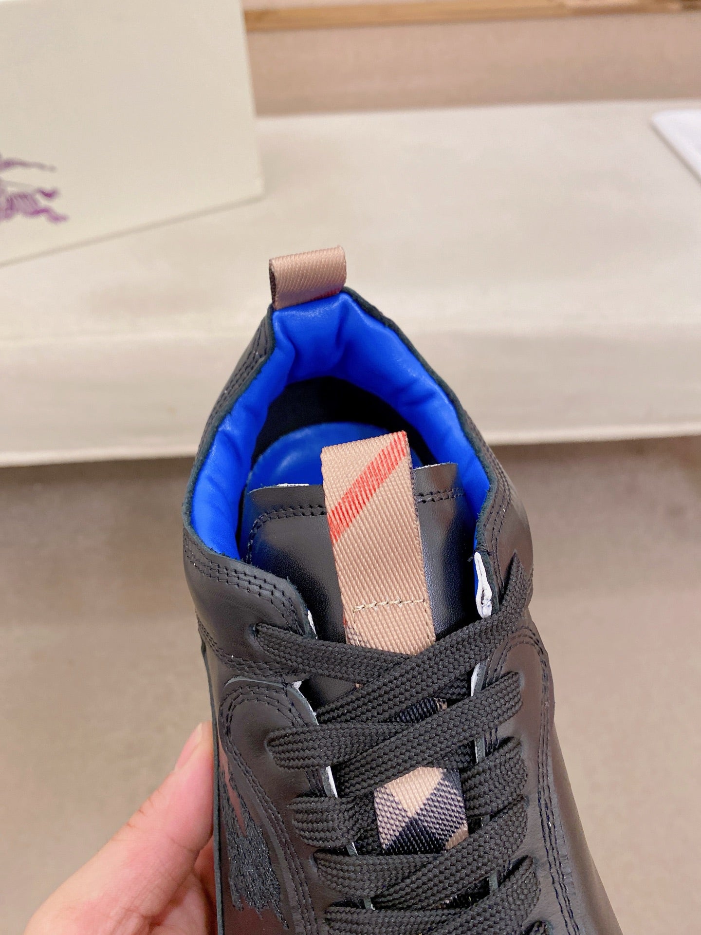Black sneaker tongue with blue lining and red plaid patch