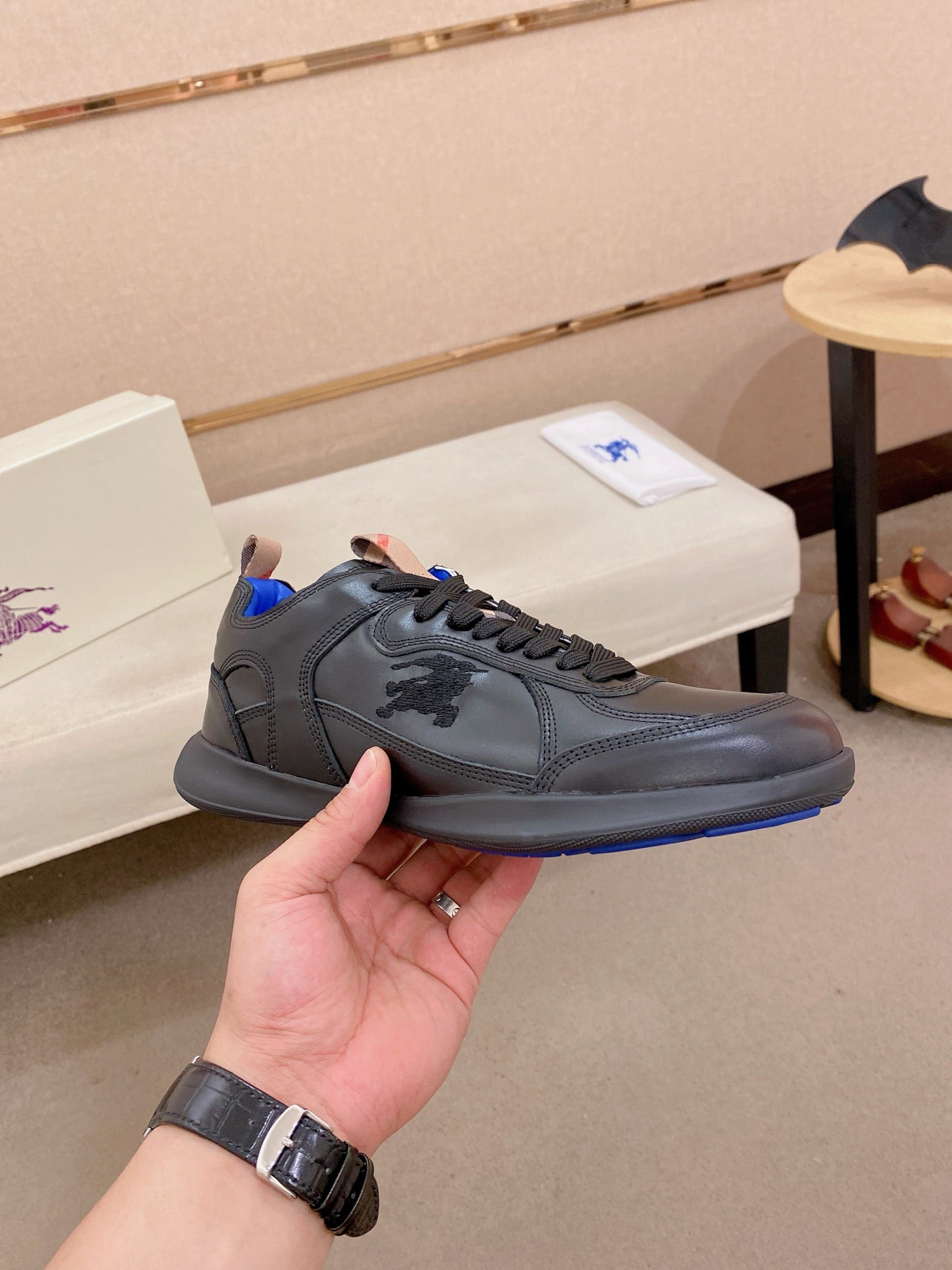Black lace-up sneaker with blue outsole edge and logo-embossed side panel