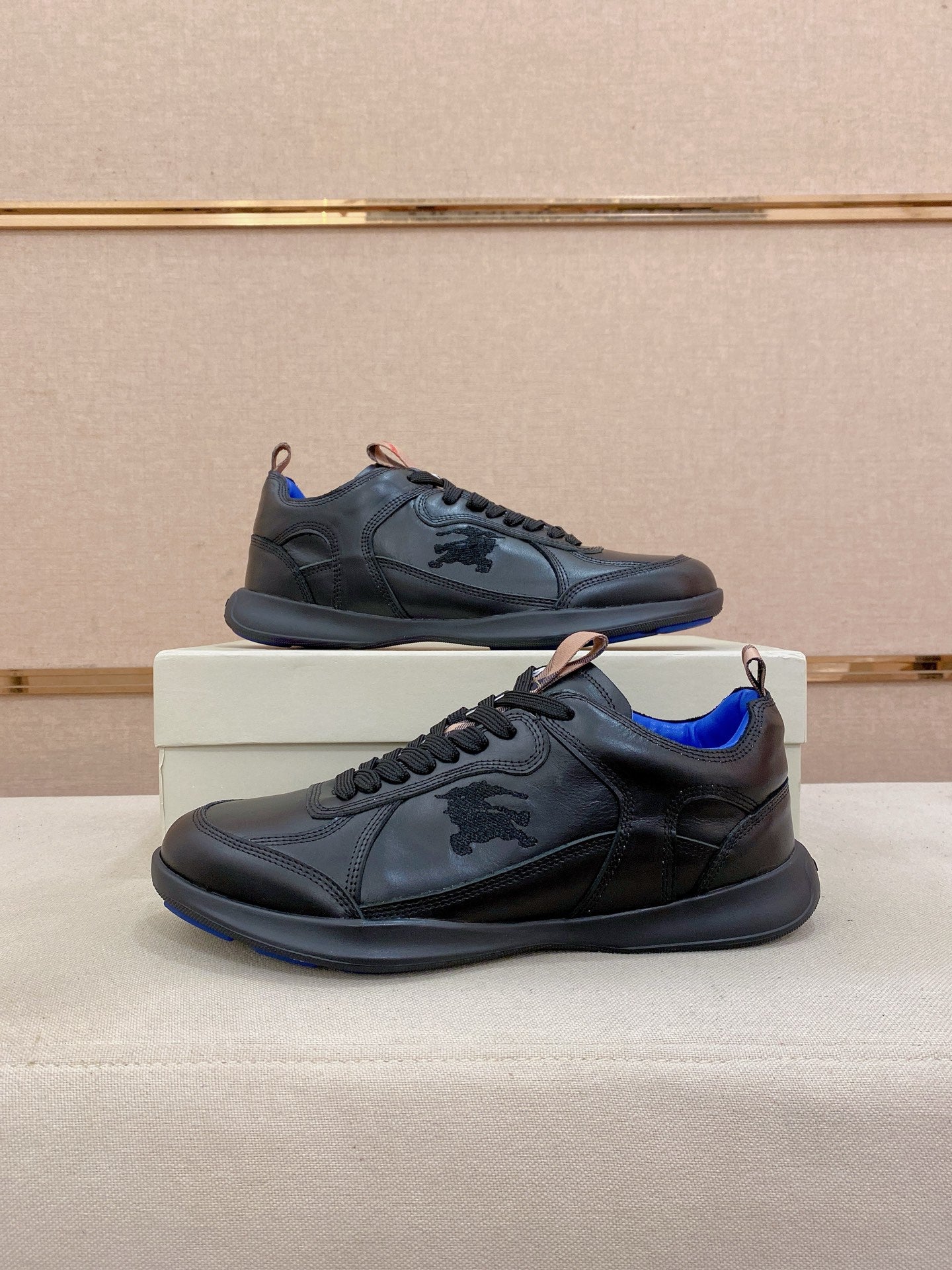 Black lace-up sneakers on display with blue accents and rubber sole
