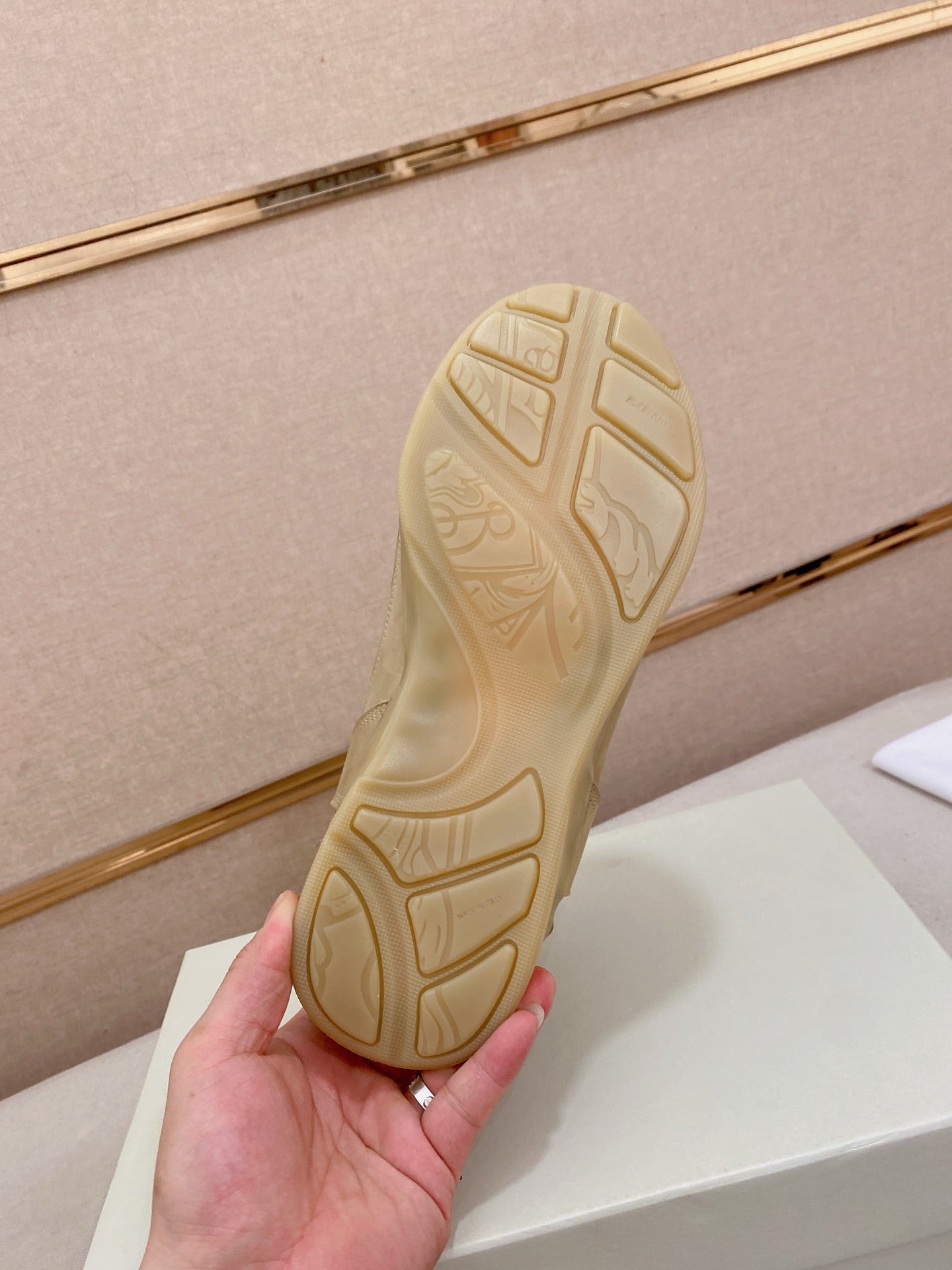 Cream sneaker outsole with tread pattern and molded logo on rubber sole