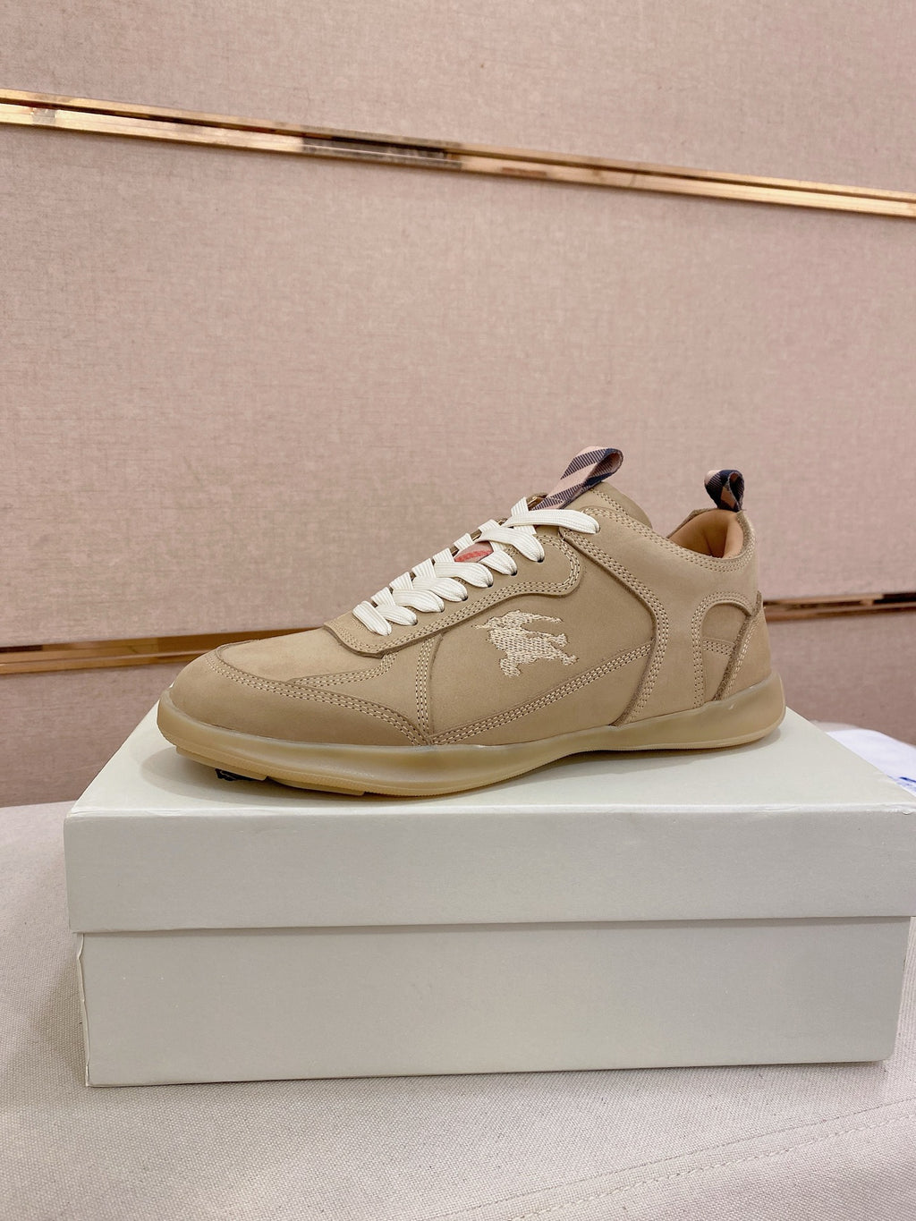 Beige lace-up sneaker with white laces, stitched upper, and low-profile rubber sole