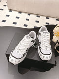White Chanel sneakers with black trim and patterned side logos, lace-up