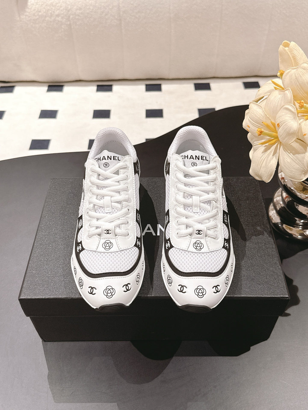 Pair of white Chanel sneakers with black trim and logo print, lace-up