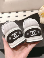 White low-top sneakers with black heel panels showing Chanel CC logos, back view