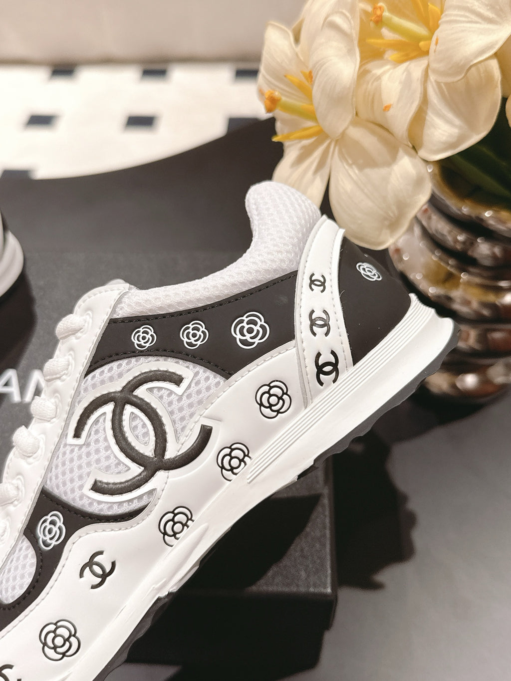 Close-up of white Chanel sneakers with black side stripe and CC logo detail