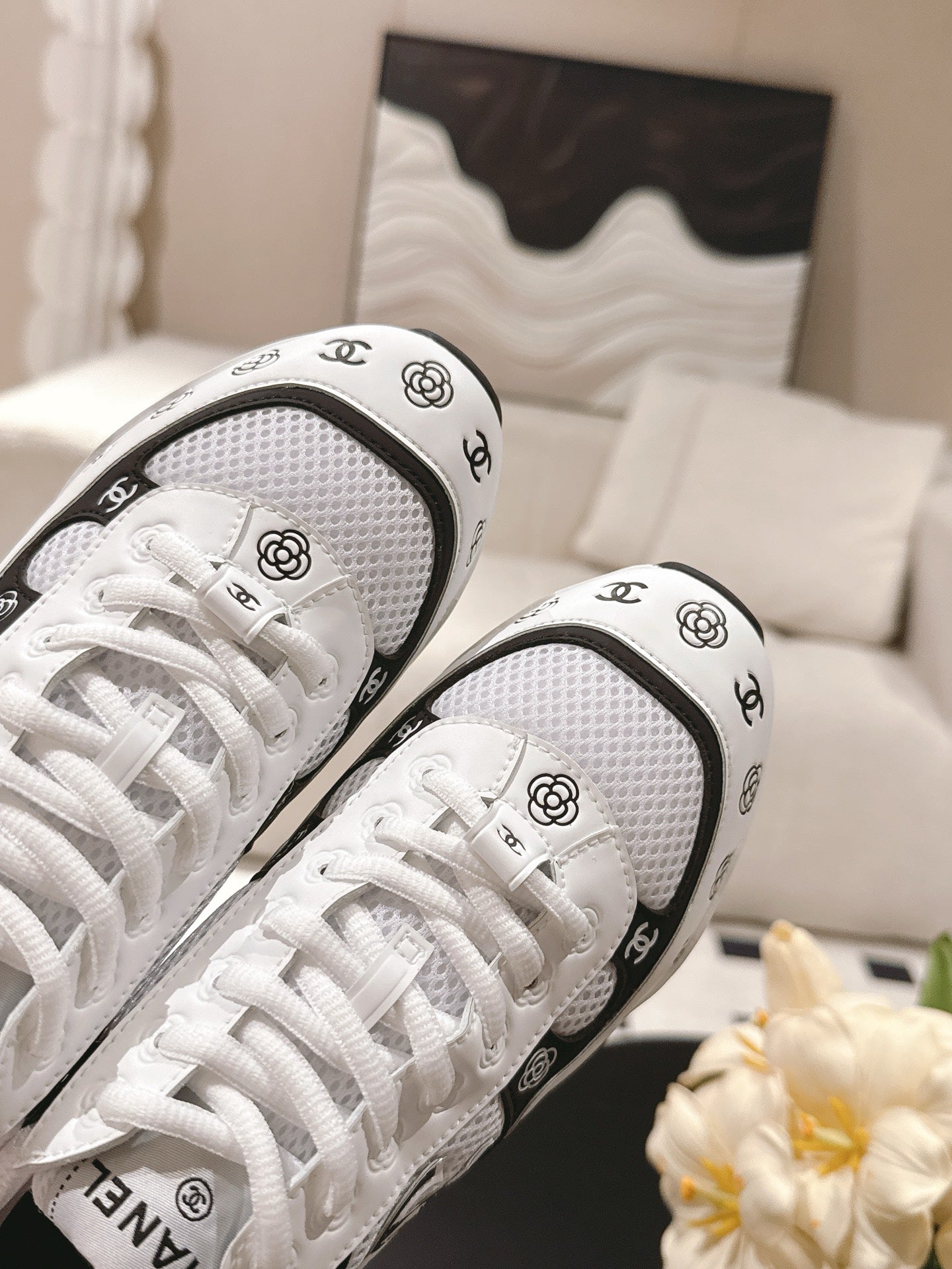 White sneaker pair close-up of textured toe, laces, and Chanel CC side detail